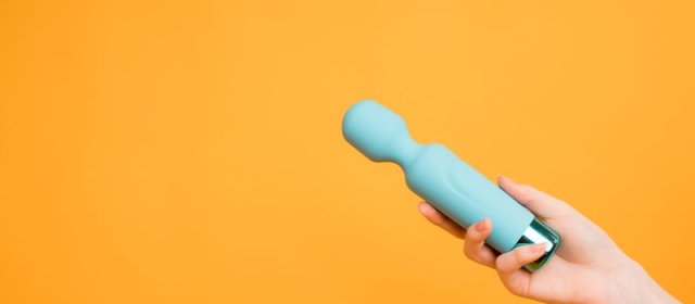 a yellow background reveals a hand holding a blue vibration device.