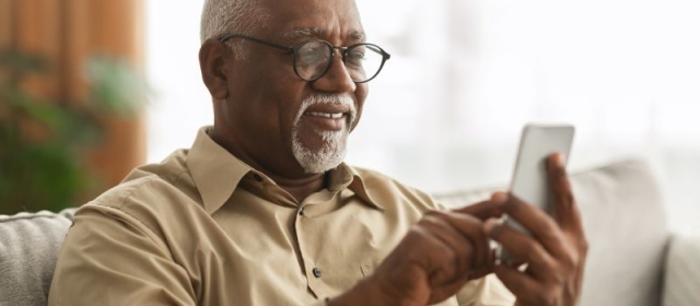ageing man with graying and balding head and beard, scrolling on cellphone