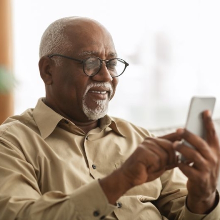 ageing man with graying and balding head and beard, scrolling on cellphone