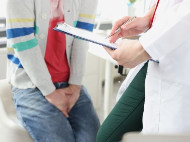 Man with hand over jeans and doctor in frame