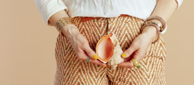 woman holding shell over orange chevron-patterned shorts