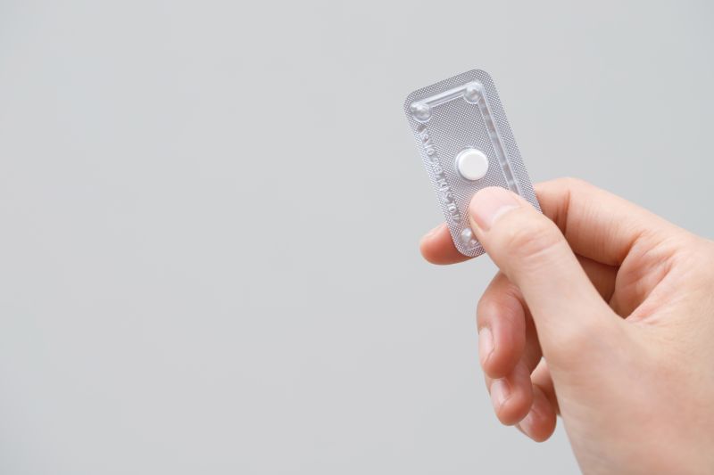 Hand holding single dose of hormonal emergency contraceptive pill