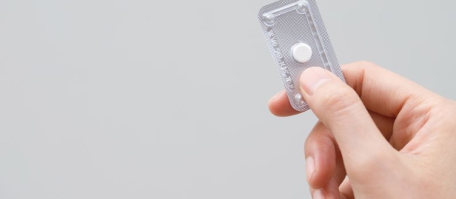 Hand holding single dose of hormonal emergency contraceptive pill