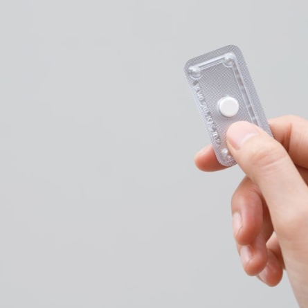 Hand holding single dose of hormonal emergency contraceptive pill