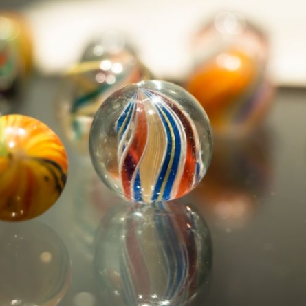 Marble with a blue, red, yellow, and white twist in the middle