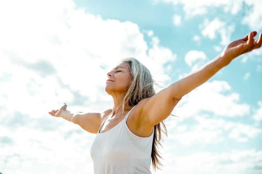 Woman with arms outstretched breathing in outdoor air