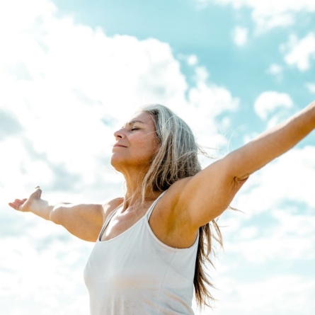 Woman with arms outstretched breathing in outdoor air