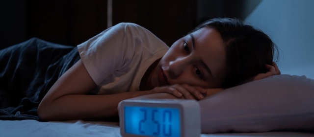 woman staring at clock in the early morning