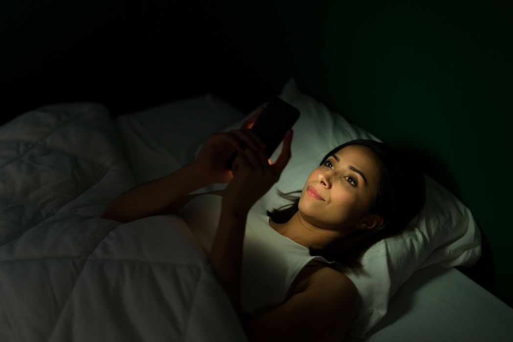 woman in bed on her phone