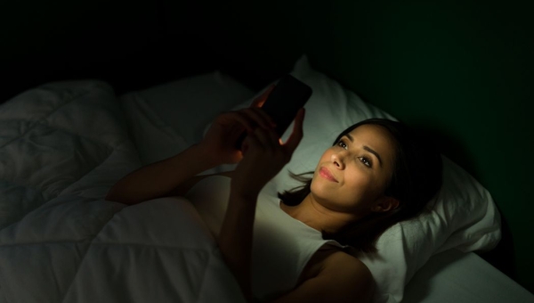 woman in bed on her phone